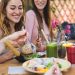 Happy friends lunching with healthy food in bar coffee brunch - Young people having fun eating meal and drinking smoothies fresh fruits in rustic restaurant - Health nutrition lifestyle concept