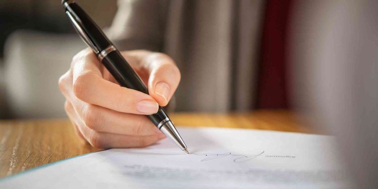 A woman signing a personal home loan application form.