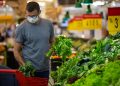Alarmed male wears medical mask against coronavirus while grocery shopping in supermarket or store- health, safety and pandemic concept - young man wearing protective medical mask for protection from virus covid-19 and stockpiling food